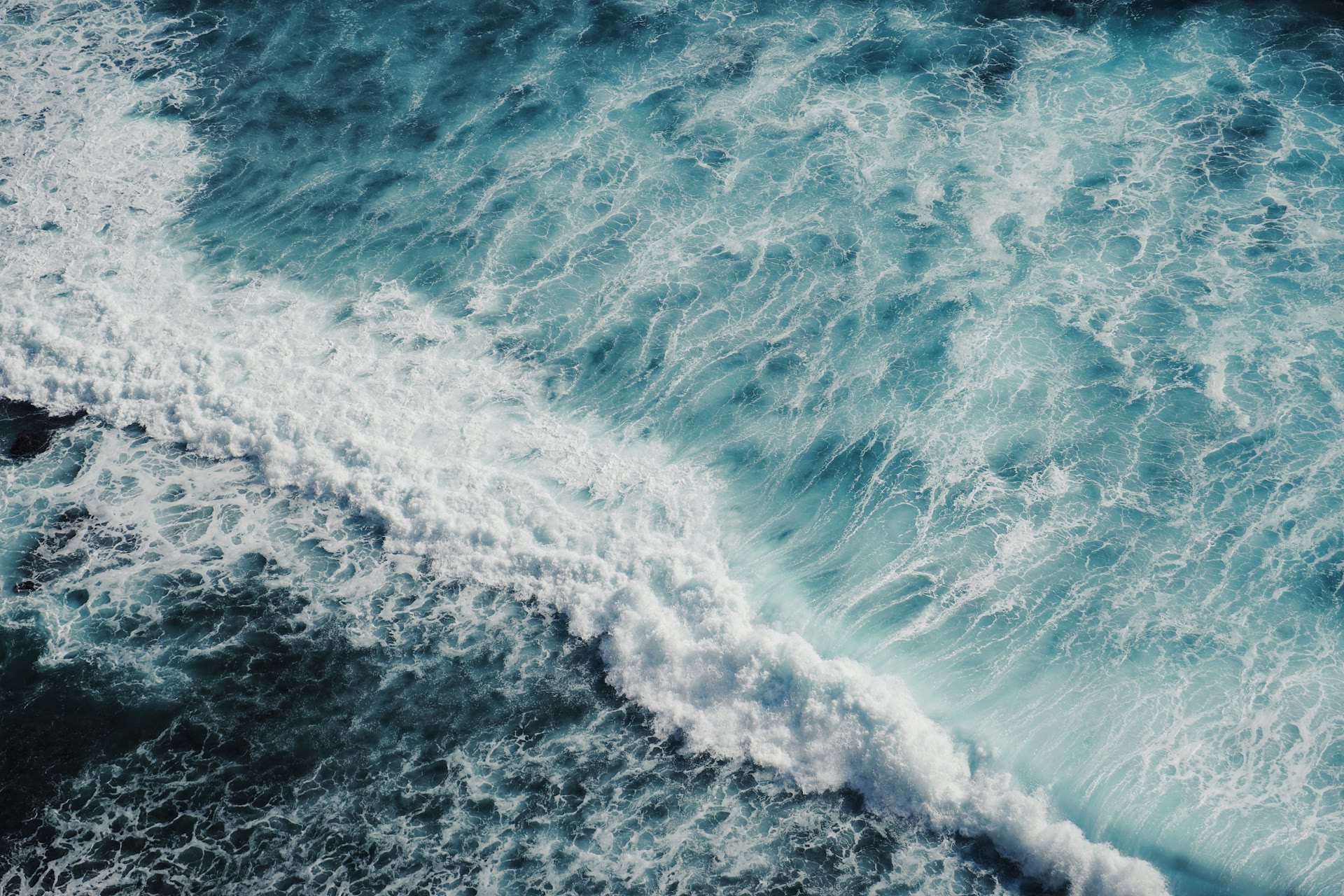 Aerial view of ocean waves rolling across deep blue water.